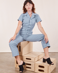 Alex is wearing Short Sleeve Jumpsuit in Periwinkle and sitting on a stack of wooden crates