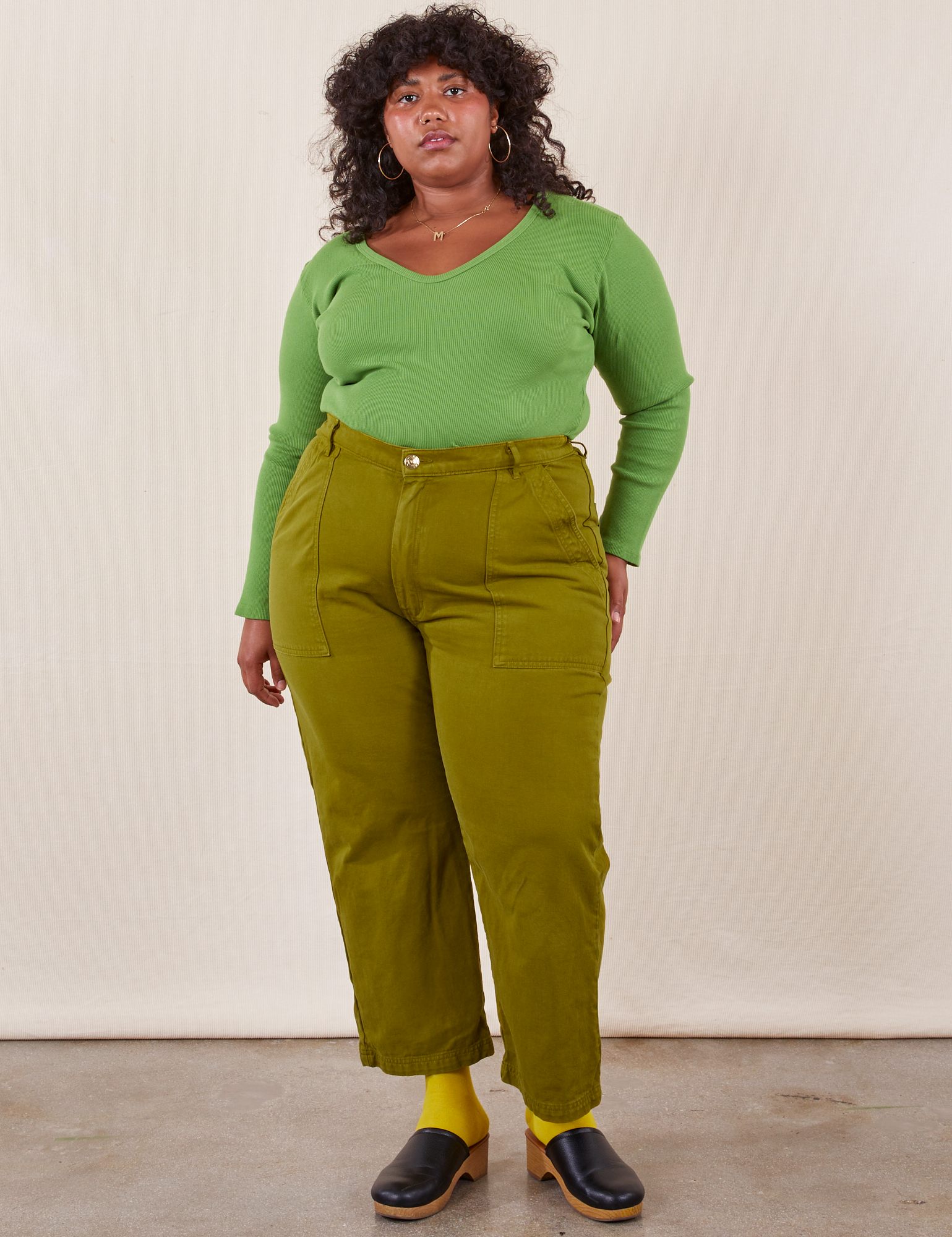 Morgan is 5&#39;5&quot; and wearing Petite 1XL Work Pants in Olive Green paired with bright olive Long Sleeve V-Neck Tee