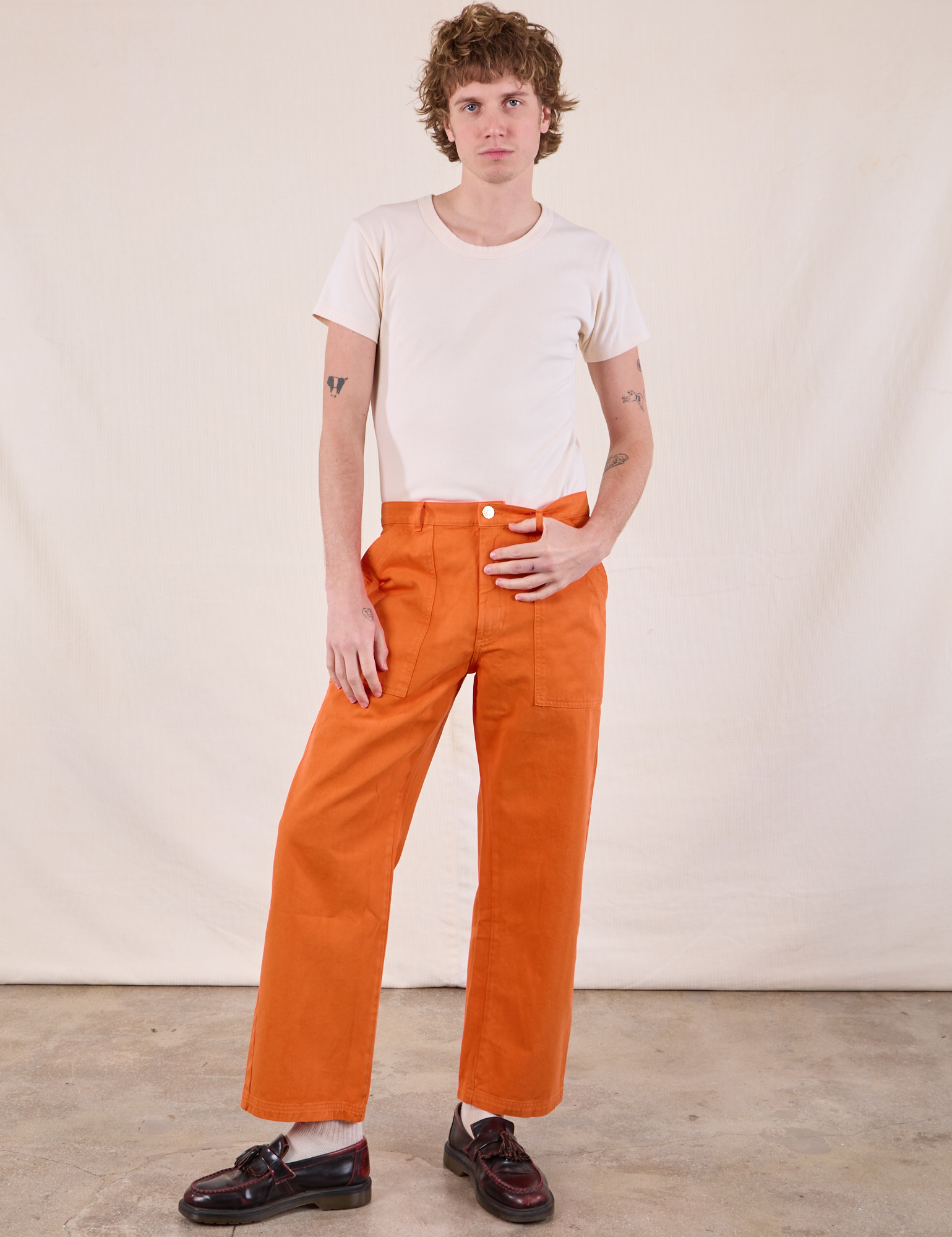 Quinn is 6’4” and wearing M Work Pants in Construction Orange paired with Burly Tee in Vintage Tee Off-White