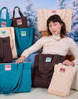 Alex is surrounded by Quilted Totes in Marine Blue, Espresso Brown and Vintage Tee Off-White