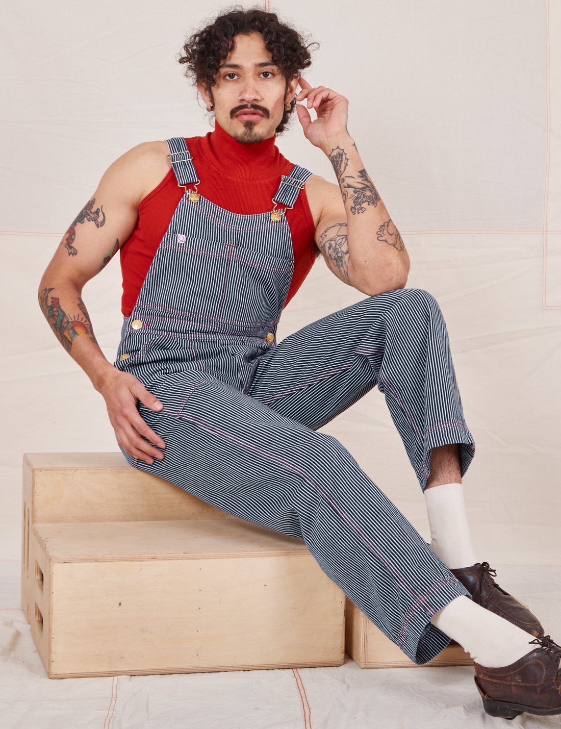Jesse is 5'8" and wearing XXS Railroad Stripe Denim Original Overalls paired with paprika Sleeveless Turtleneck 