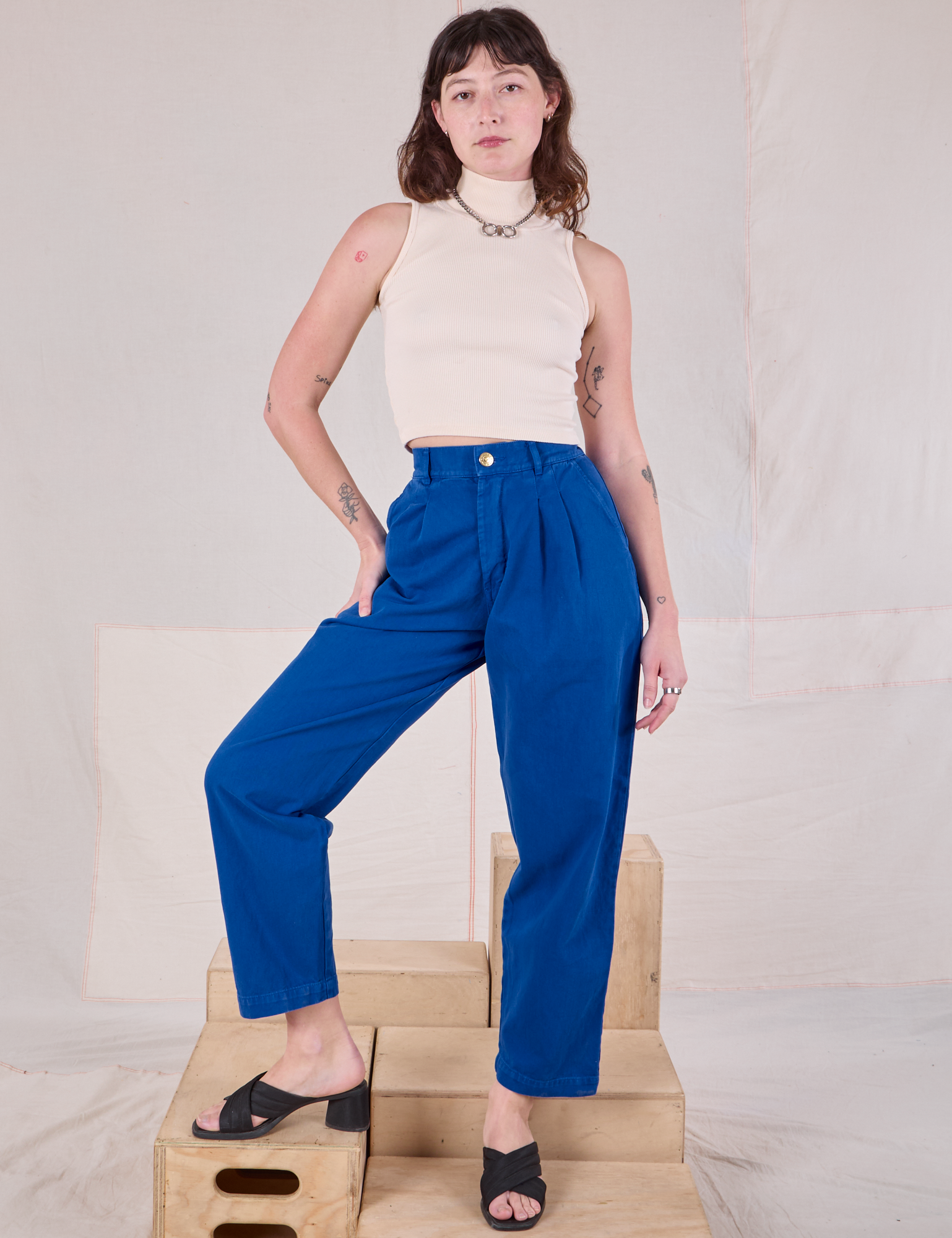 Alex is 5'8" and wearing XXS Heavyweight Trousers in Royal Blue paired with a Sleeveless Turtleneck in Vintage Tee Off-White