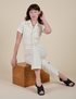 Alex is wearing Short Sleeve Jumpsuit in Vintage Tee White