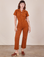 Alex is 5'8" and wearing XS Short Sleeve Jumpsuit in Burnt Terracotta