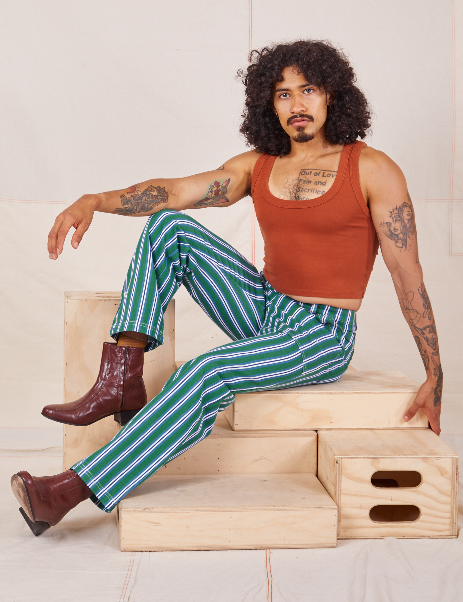Jesse is wearing Stripe Work Pants in Green paired with burnt terracotta Cropped Tank