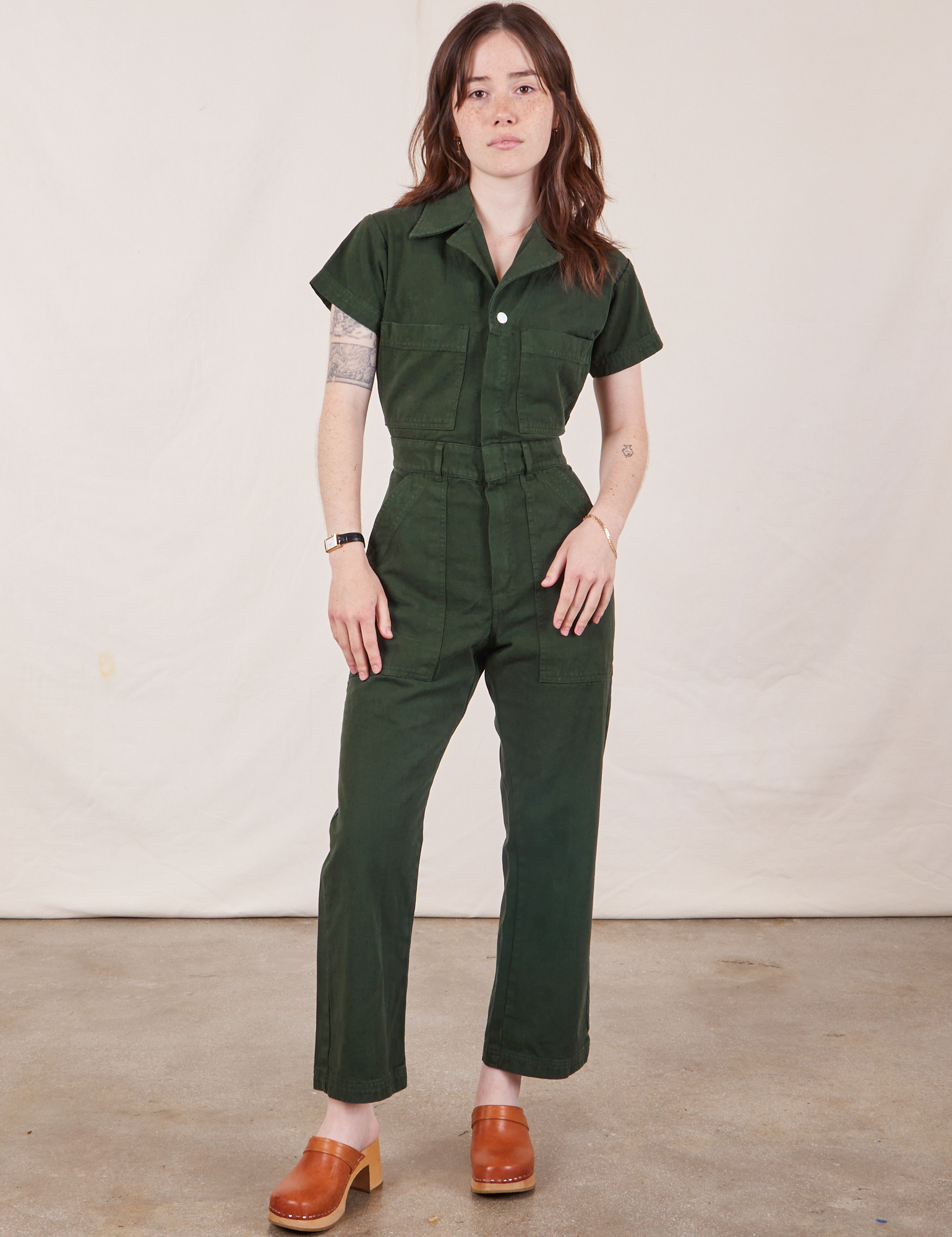 Hana is 5’3” and wearing XXS Petite Short Sleeve Jumpsuit in Swamp Green