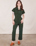 Hana is 5’3” and wearing XXS Petite Short Sleeve Jumpsuit in Swamp Green