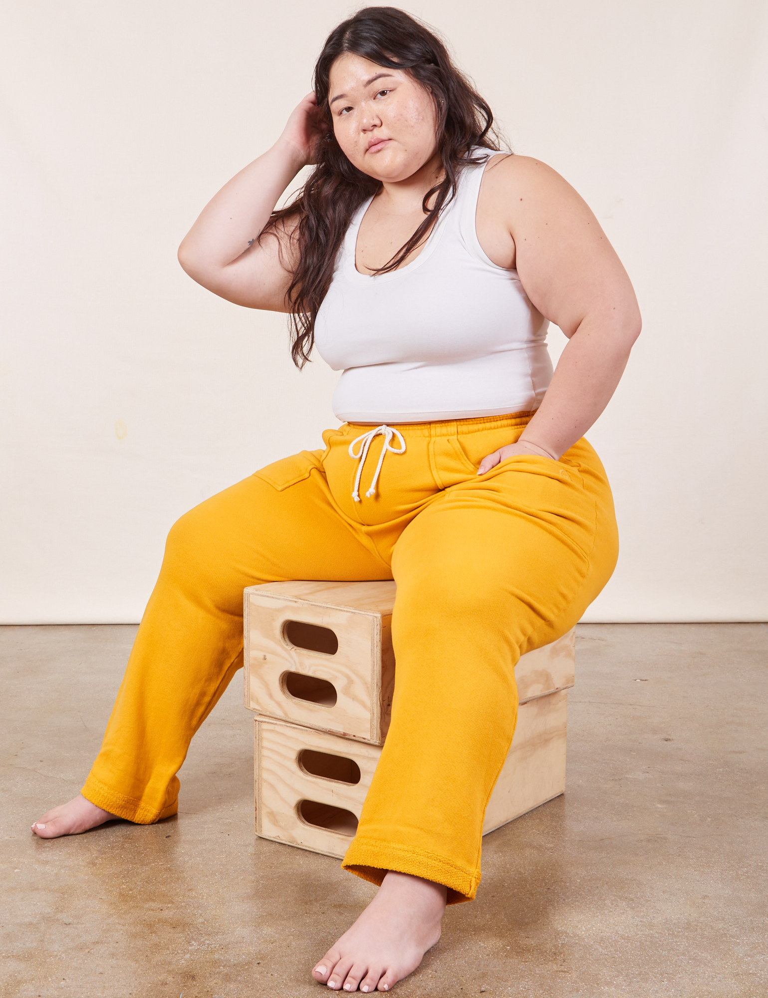 Ashley is wearing Cropped Rolled Cuff Sweatpants in Mustard Yellow and vintage off-white Cropped Tank Top
