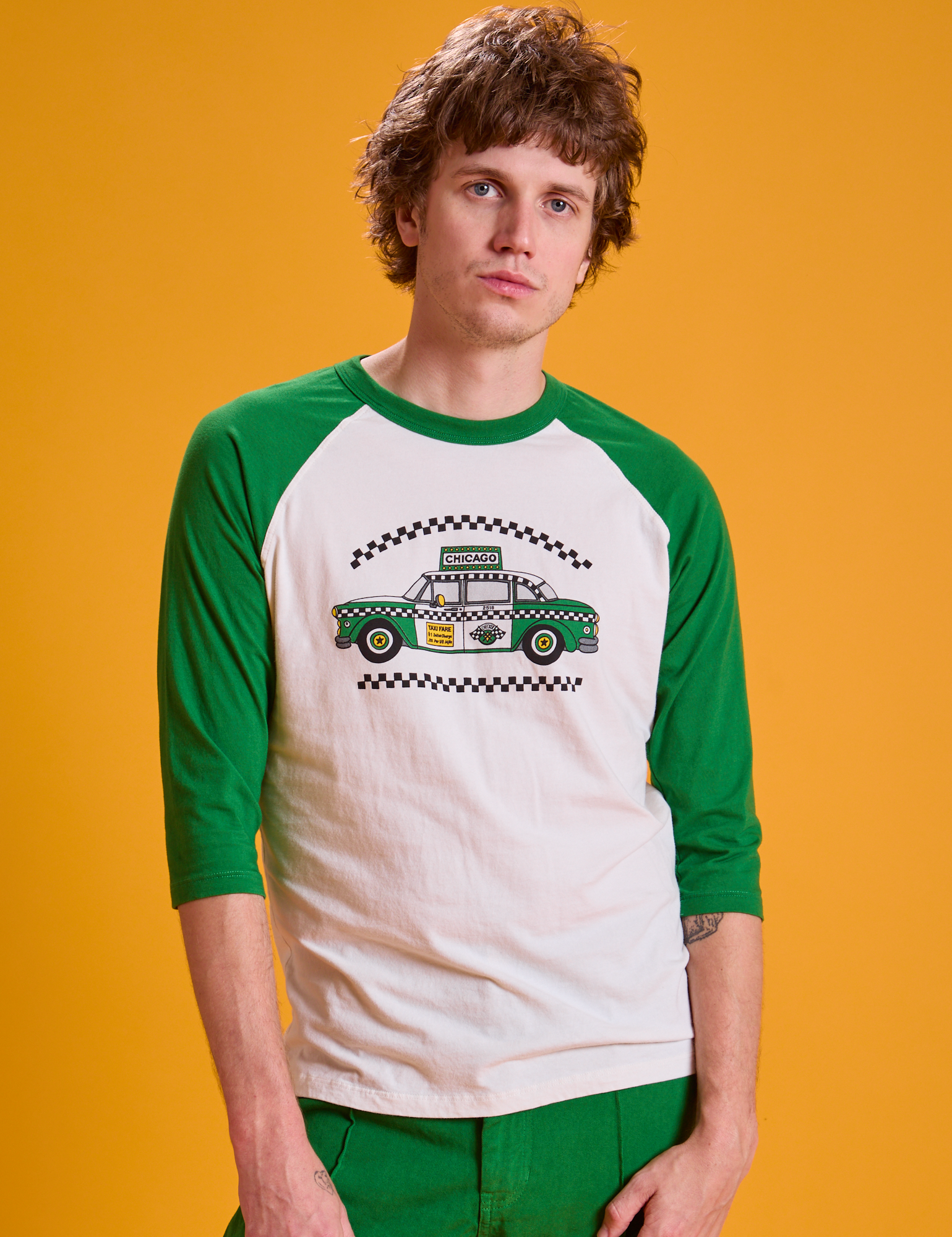 Quinn is 6'3" and wearing M Taxi Raglan Tee in Chicago. White body with green sleeves.