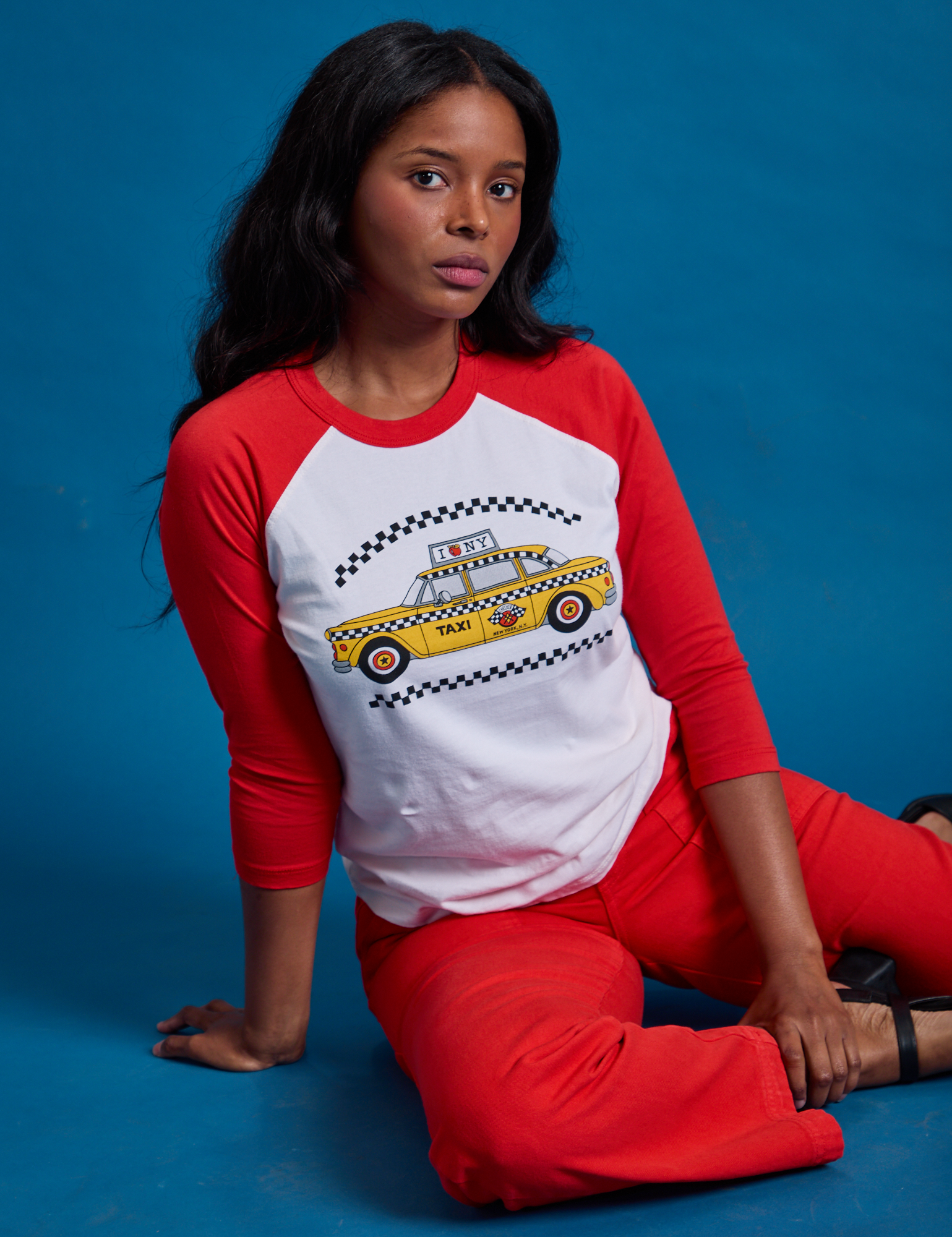 Kandia is wearing the Taxi Raglan Tee in NYC featuring a yellow taxi graphic.