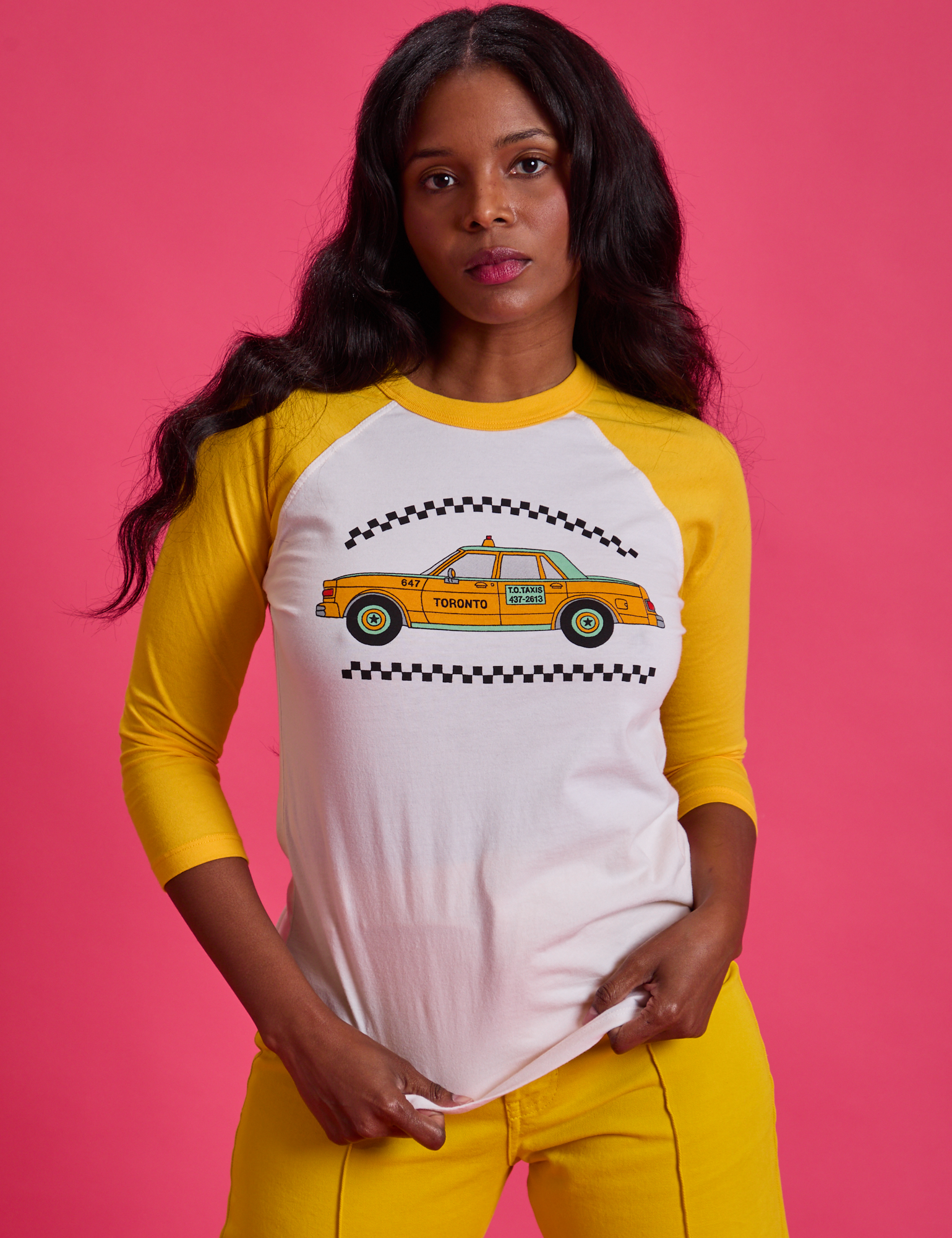 Kandia is 5'3" and wearing XS Taxi Raglan Tee in Toronto. White tee body with yellow raglan sleeves.