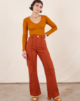 Soraya is 5'2" and wearing XXS Petite Western Pants in Burnt Terracotta paired with a burnt orange Long Sleeve V-Neck Tee. 