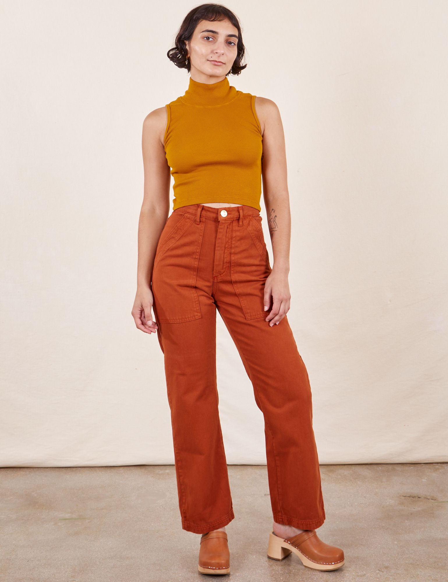 Soraya is 5&#39;2&quot; and wearing Petite XXS Work Pants in Burnt Terracotta paired with Sleeveless Turtleneck in Spicy Mustard