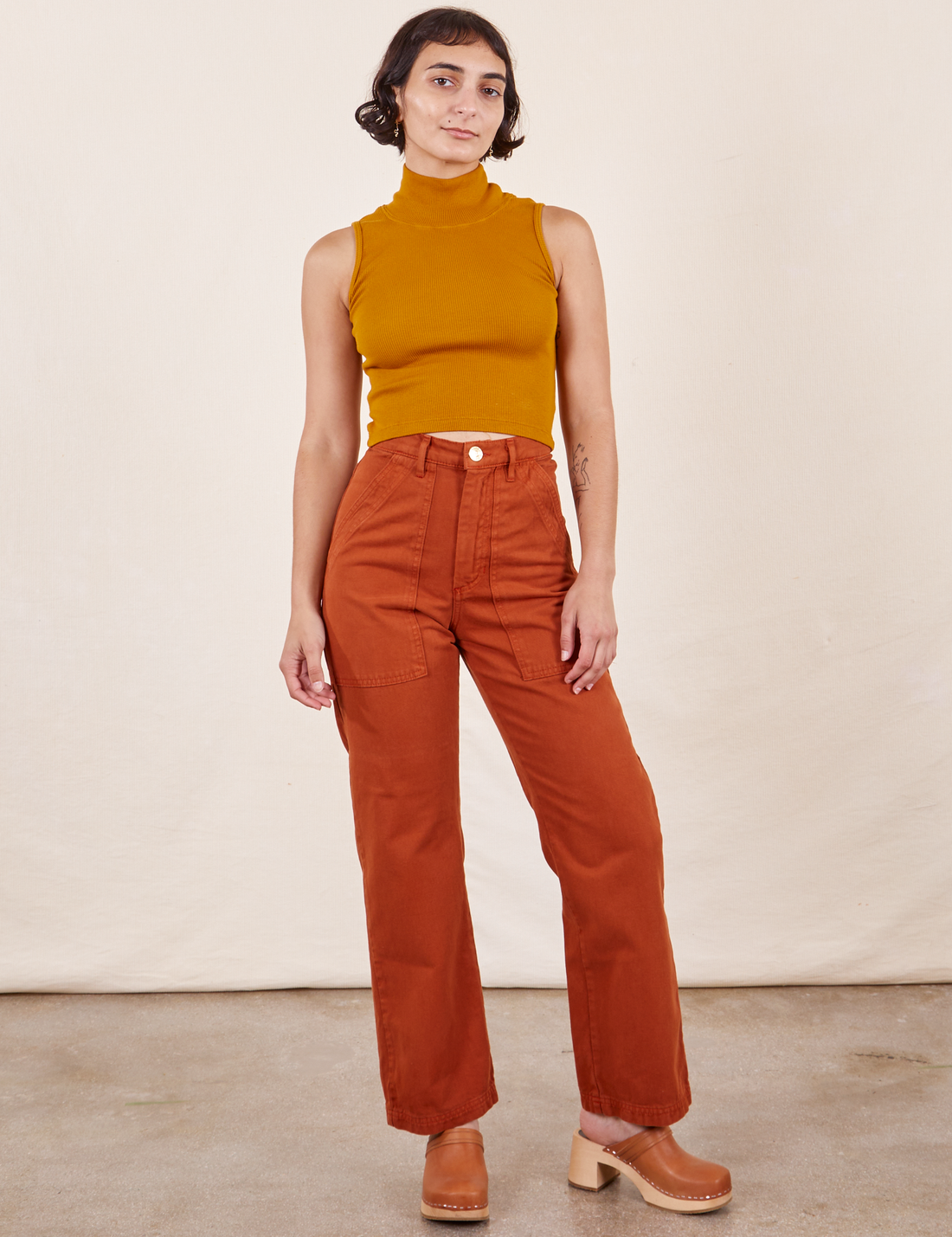 Soraya is 5'2" and wearing Petite XXS Work Pants in Burnt Terracotta paired with Sleeveless Turtleneck in Spicy Mustard