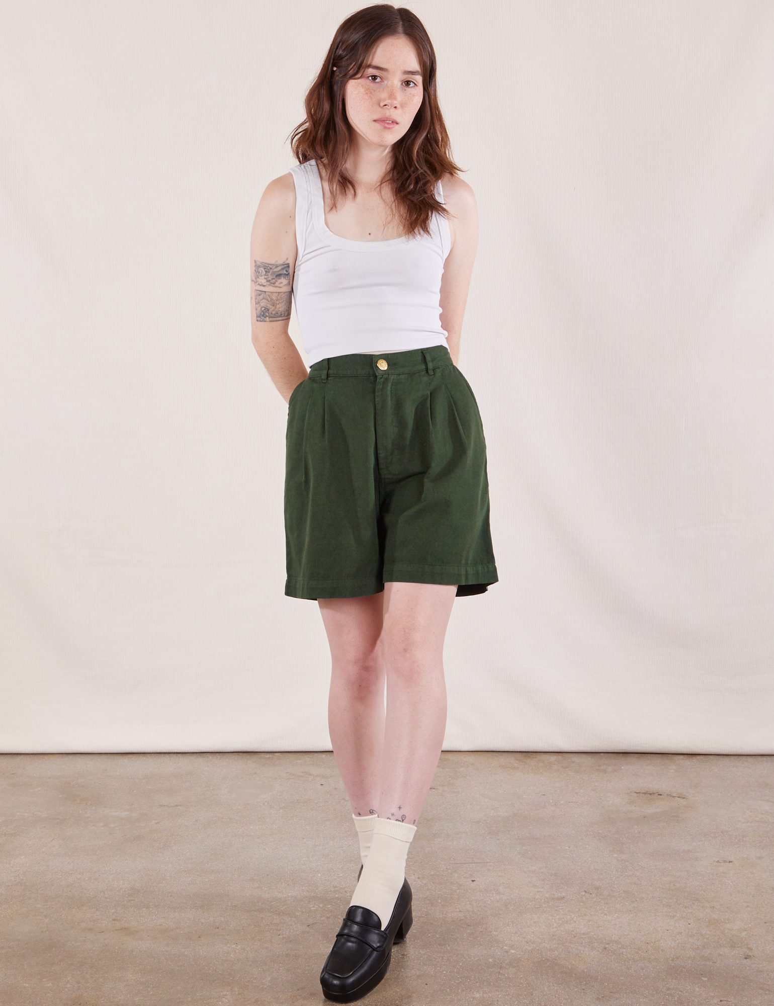 Hana is 5&#39;3&quot; and wearing XXS Trouser Shorts in Swamp Green paired with Cropped Tank Top in Vintage Tee Off-White