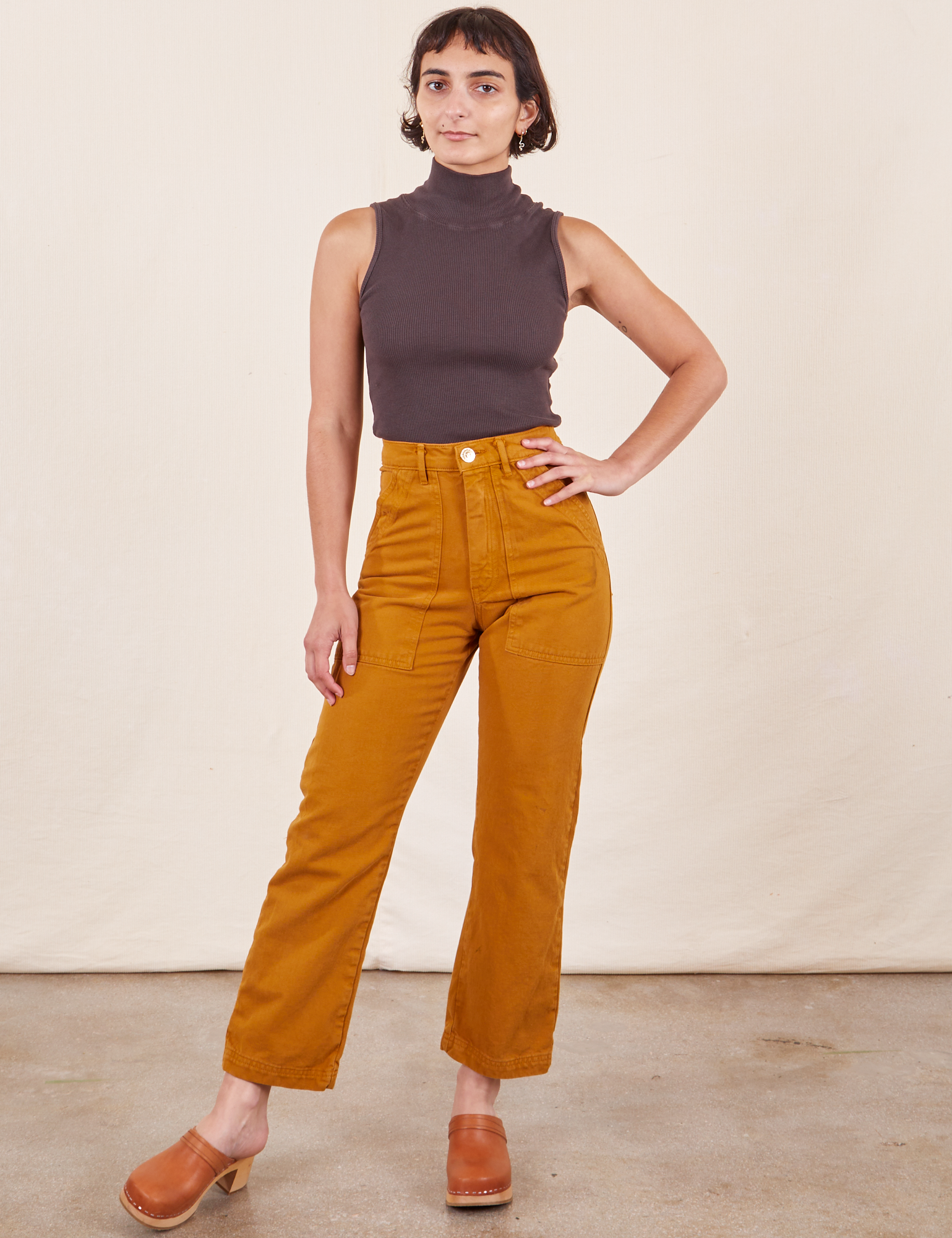 Soraya is 5&#39;2&quot; and wearing Petite XXS Work Pants in Spicy Mustard paired with an espresso brown Sleeveless Turtleneck