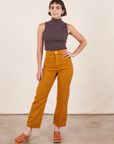 Soraya is 5'2" and wearing Petite XXS Work Pants in Spicy Mustard paired with an espresso brown Sleeveless Turtleneck