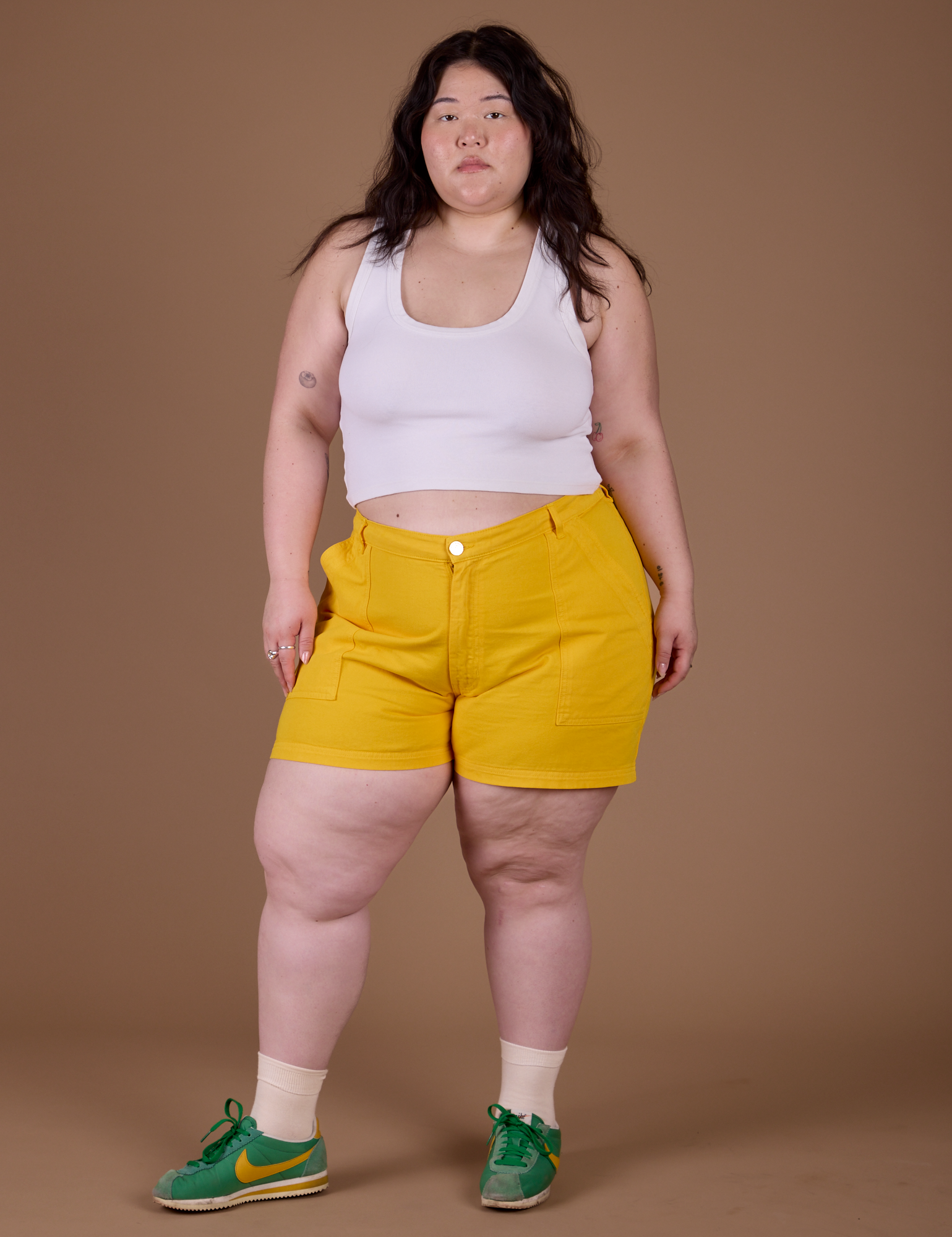 Ashley is 5’7” and wearing 1XL Classic Work Shorts in Sunshine Yellow paired with Vintage Tee White Cropped Tank