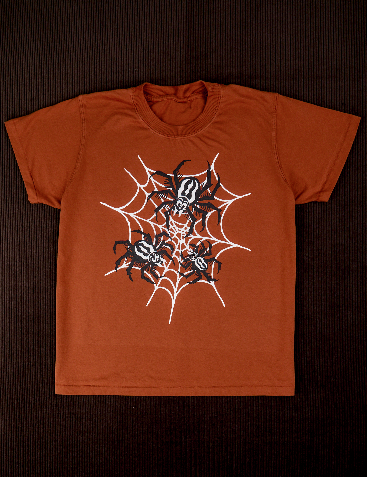 Vintage Tee in Spidey. Orange tee body with a black and white spider graphic.