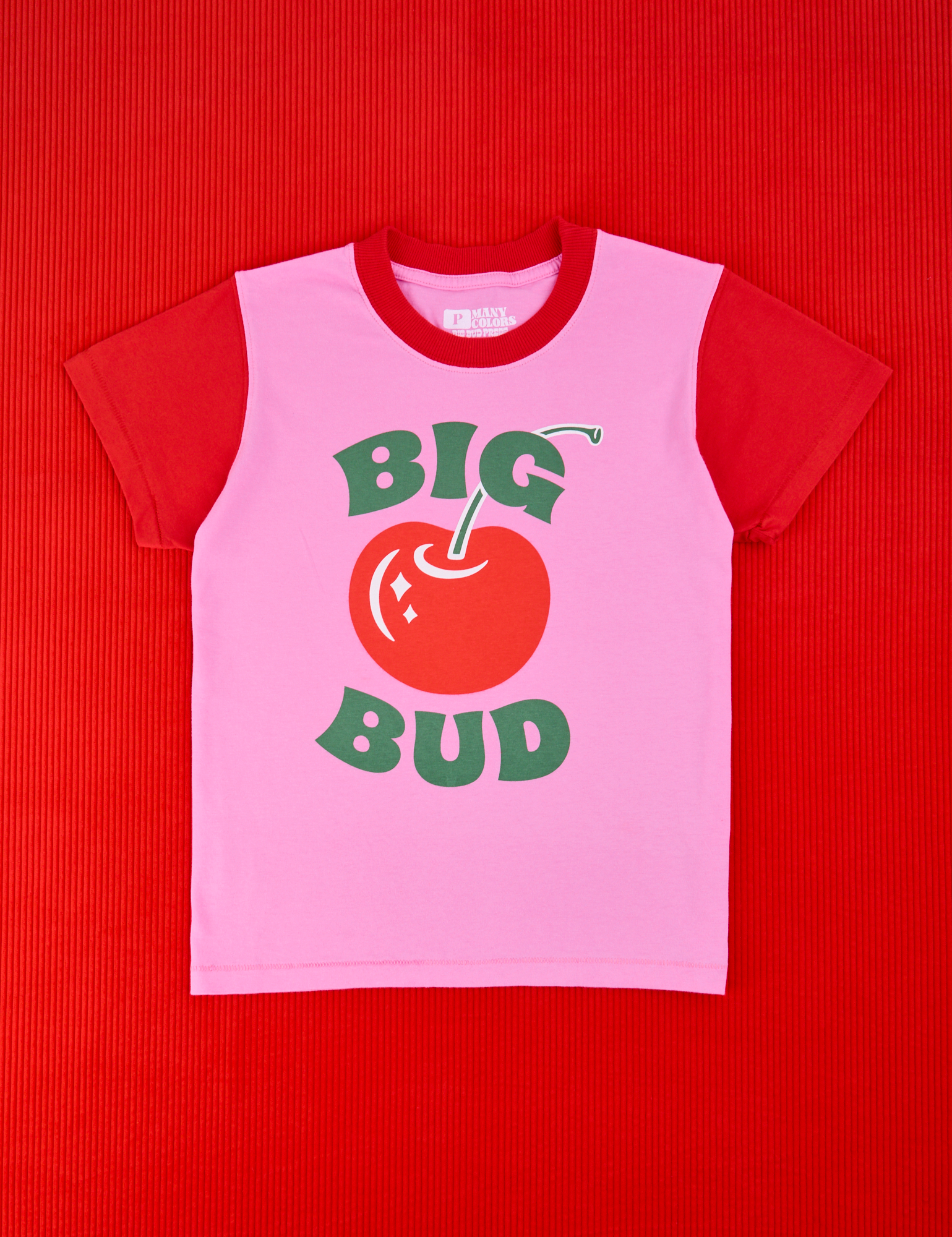 Vintage Tee in Big Red Cherry. Bubblegum pink body with mustang red sleeves. Big Bud in green text and a red cherry in the middle.