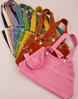Overall Handbags in a rainbow of colors. Stacked one each other and fanned out.