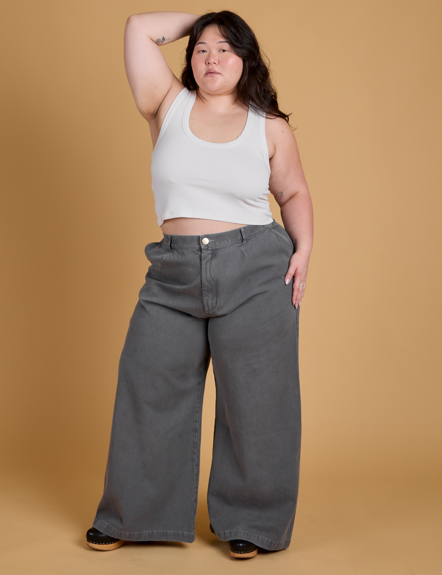 Ashley is 5'7" and wearing 1XL Heritage Wide Leg Trousers in Washed Grey paired with a vintage tee white Cropped Tank