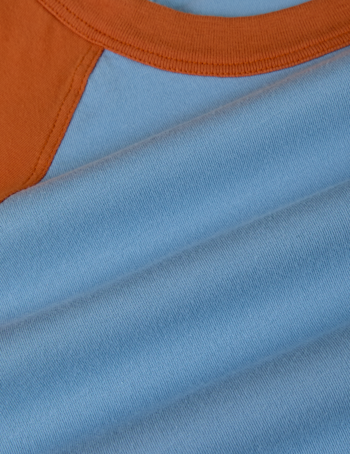 Fabric close up of the Baby Blue/Orange Colorblock Raglan Tee
