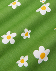 Bob Baker Flower Jumpsuit fabric detail close up. Green background with white daisy flowers and yellow centers