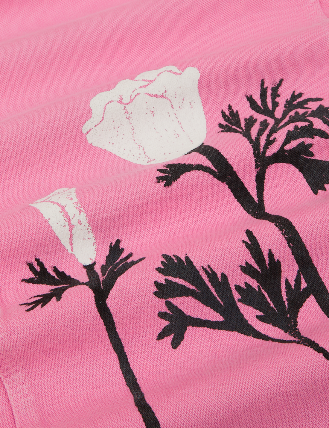 California Poppy Overalls in Bubblegum Pink fabric detail close up. Paintstamped black stems and white poppies.