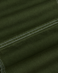 Carpenter Jeans in Evergreen fabric detail close up. White contrast stitching.