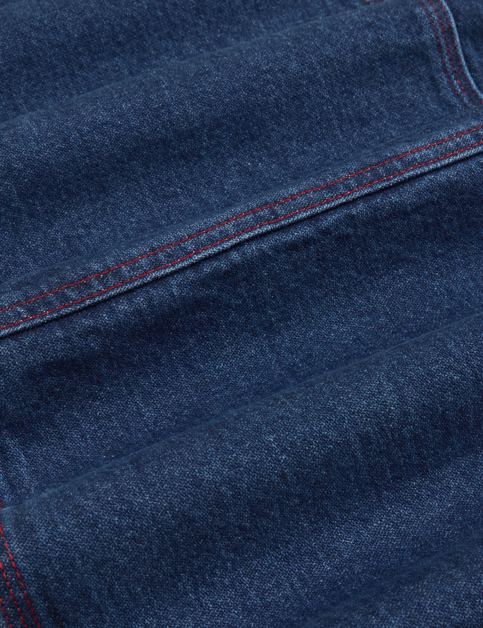 Carpenter Overalls in Dark Wash fabric detail close up. Contrast red top stitching
