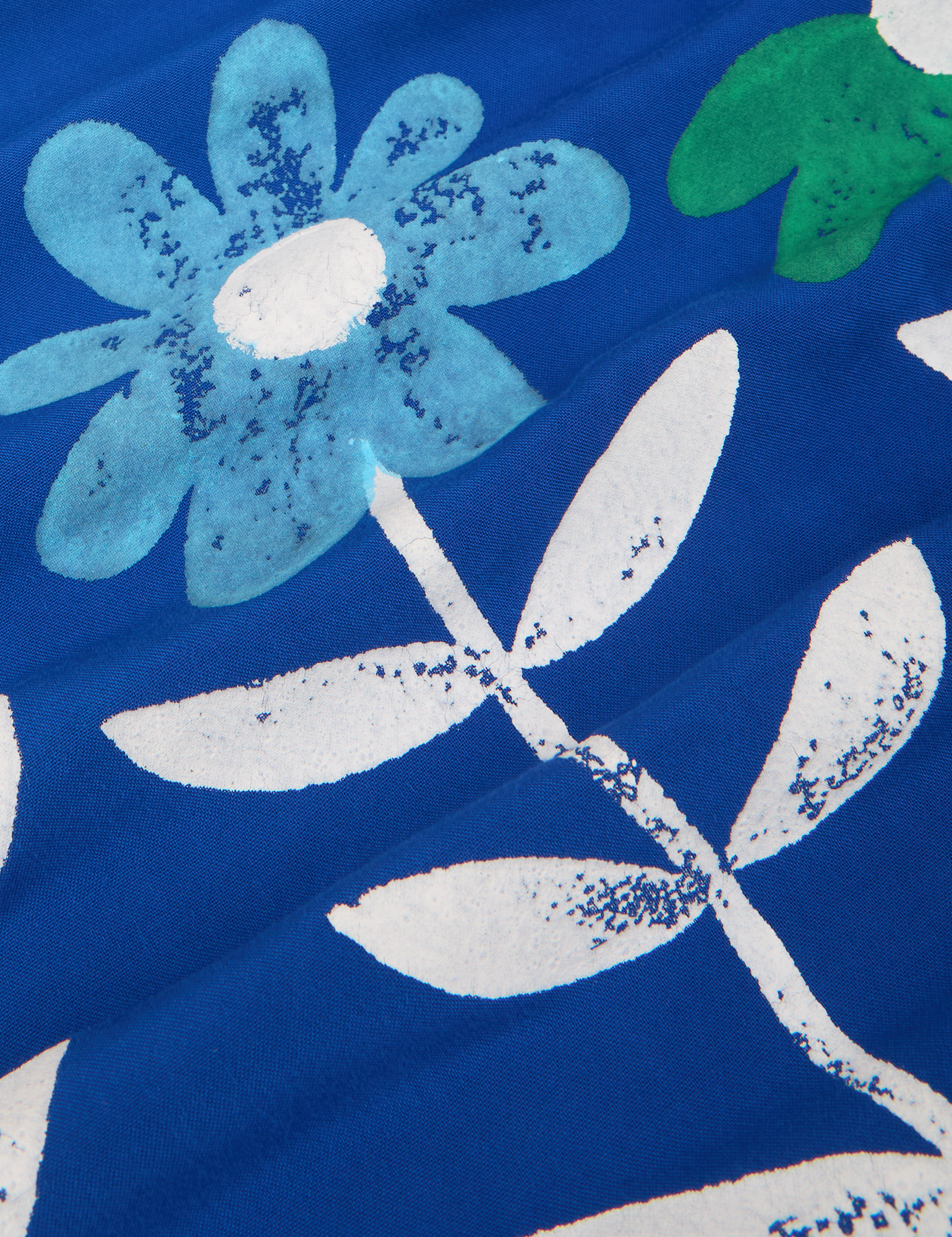 Paintstamped Pantry Button-Up in Daisy fabric close up. Baby blue flower with white leaves and stem