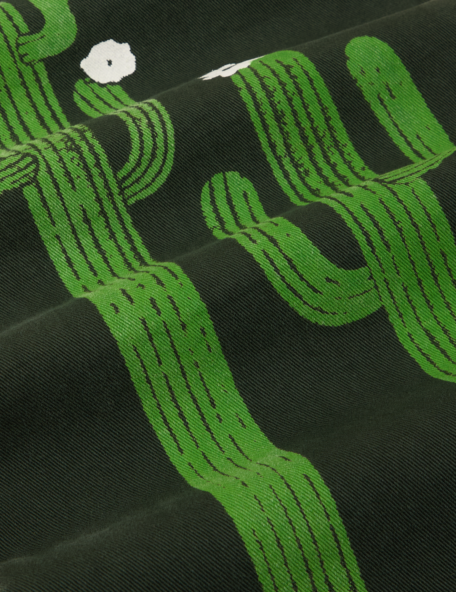 Paintstamped Work Pants in Cactus fabric detail close up. Green cactuses with white flowers. 