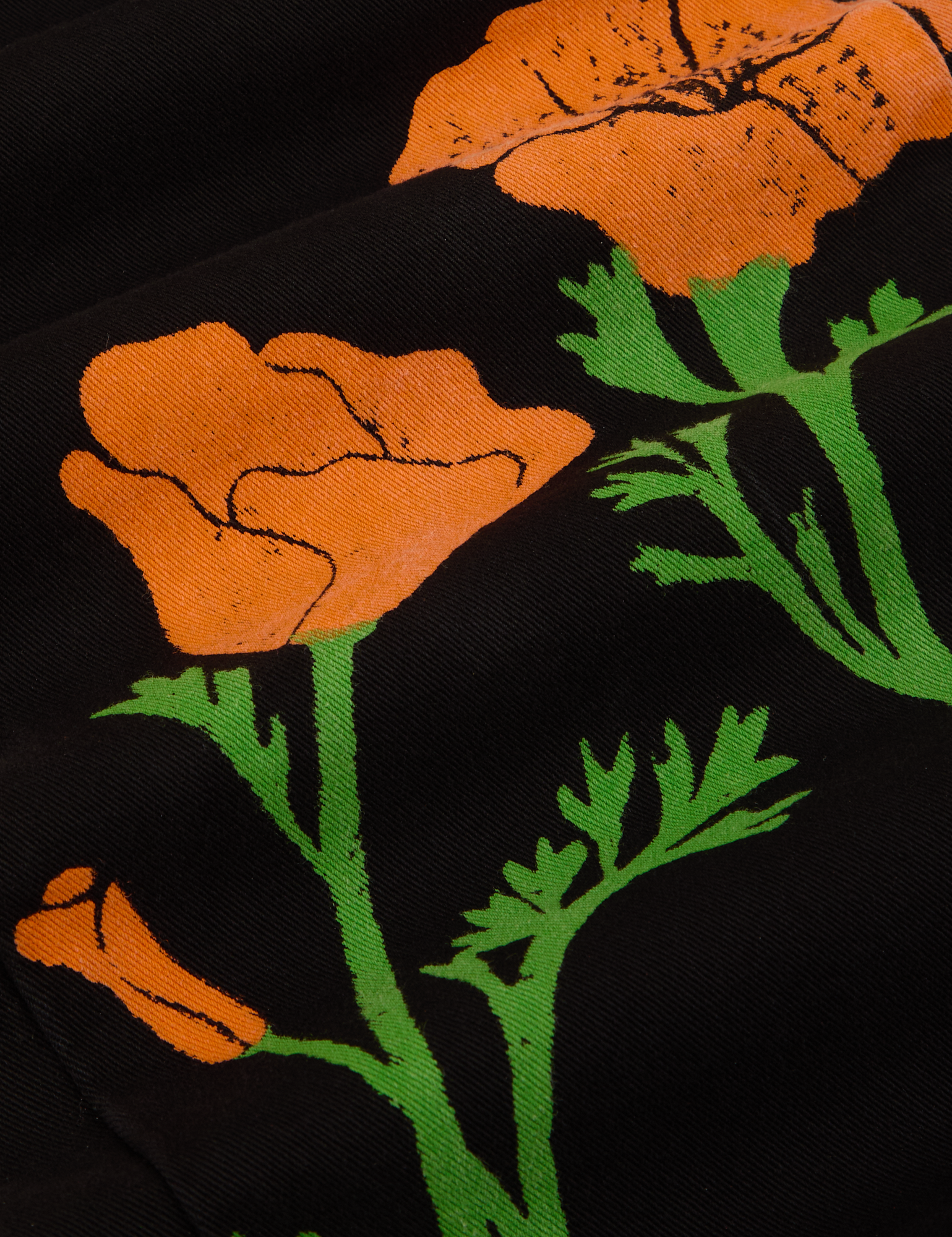 Paintstamped Work Pants in Poppy fabric detail close up. Orange poppy with green stems and leaves.