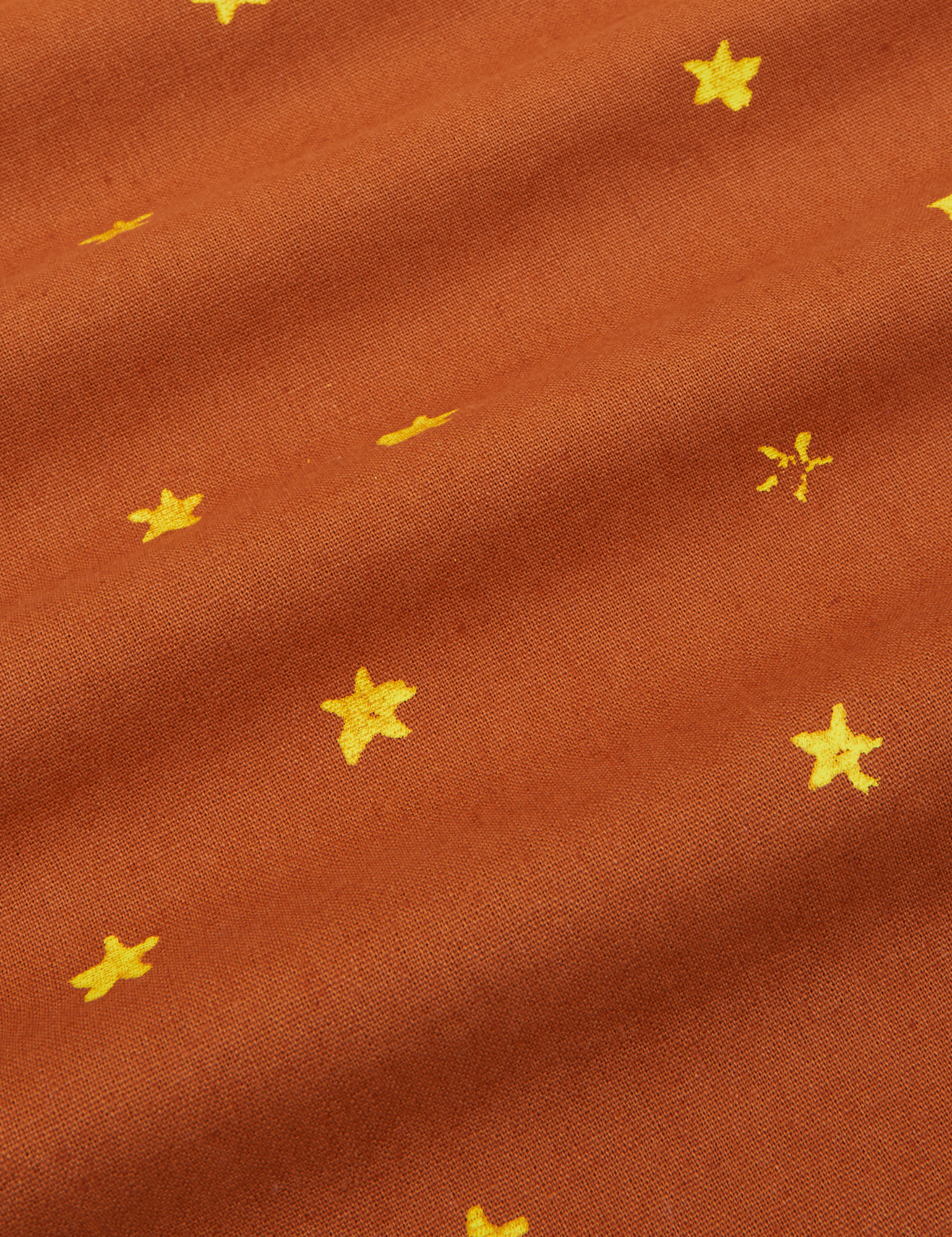 Icon Pantry Button-Up in Stars fabric detail. Close up of yellow stamped stars on a burnt terracotta top.