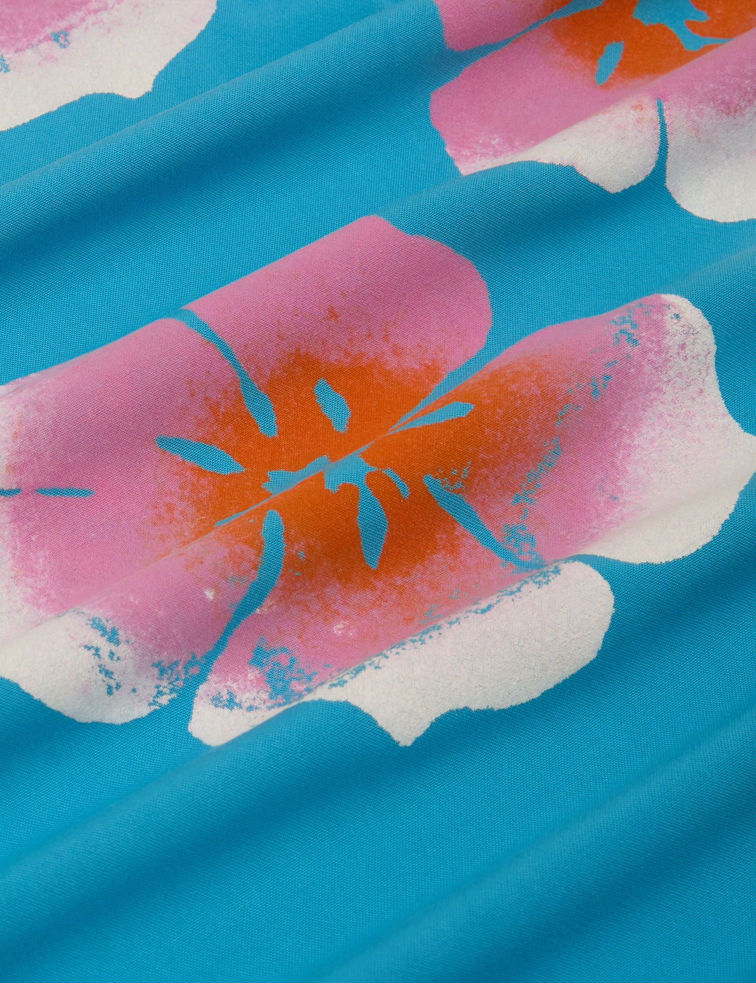 Paintstamped Pantry Button-Up in Hawaiian Blue fabric detail close up. White, pink and orange paintstamped fflowers.