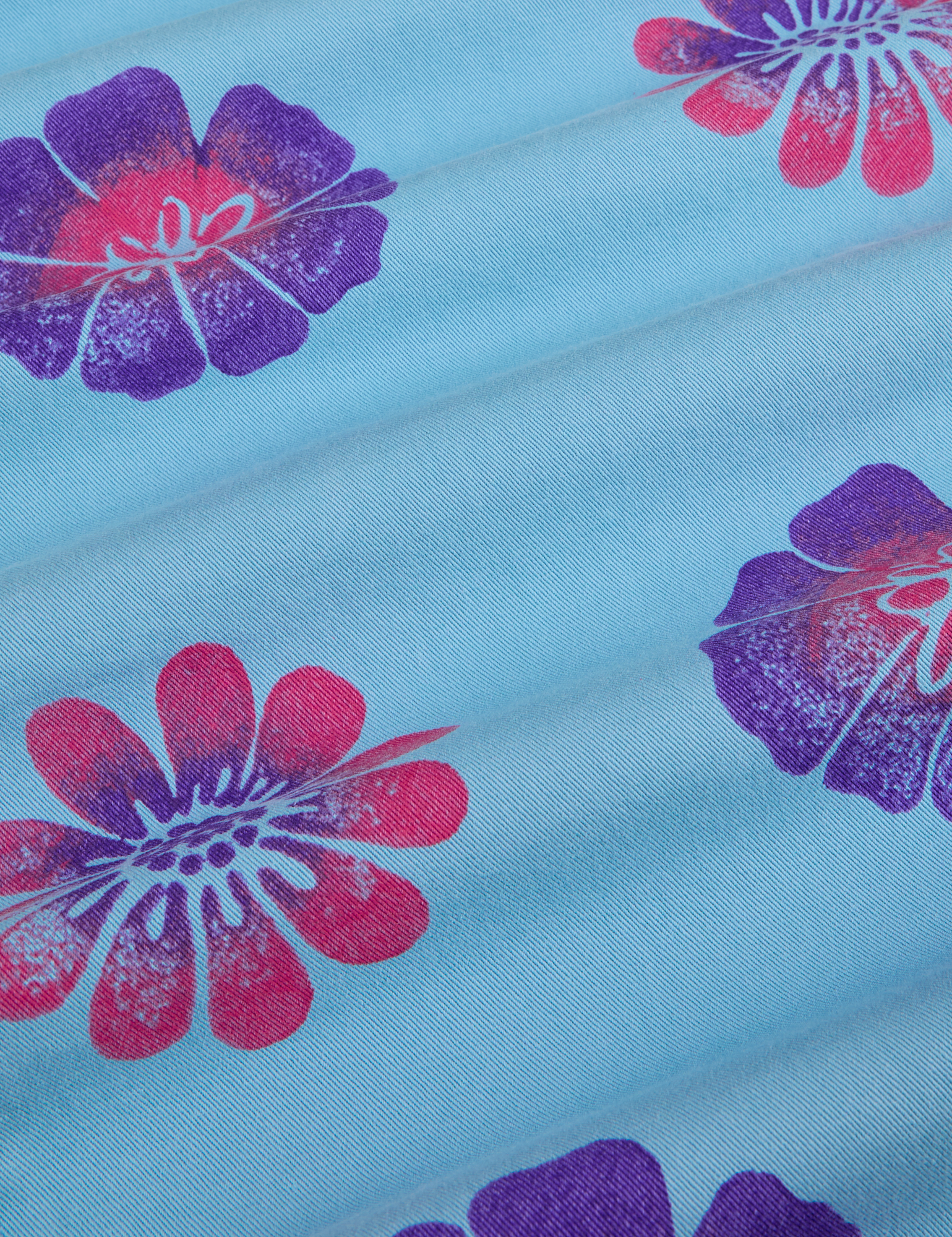 Floral Painted Work Pants in Blue fabric detail close up. Baby Blue Work Pants with paintstamped pink and purple flowers