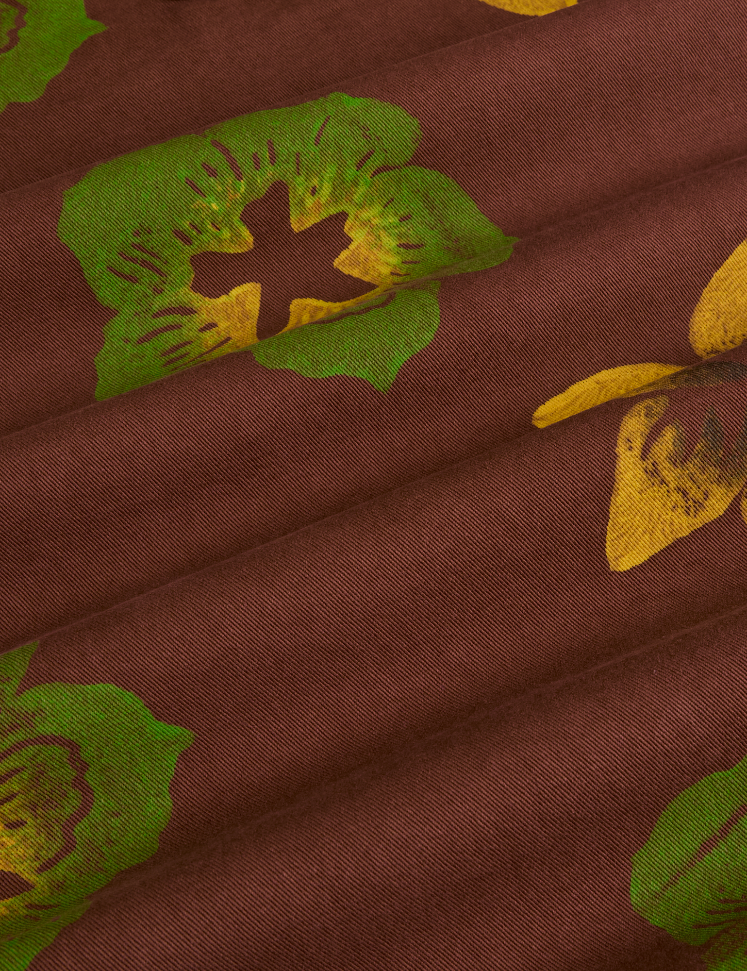 Floral Painted Work Pants in Brown fabric detail close up. Brown pant with green and yellow paintstamped flowers