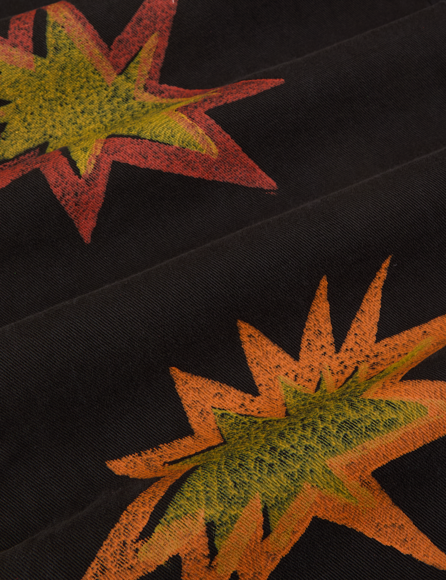 Paintstamped Work Pants in Explosion close up of paint stamped explosion shapes in orange, red and yellow.