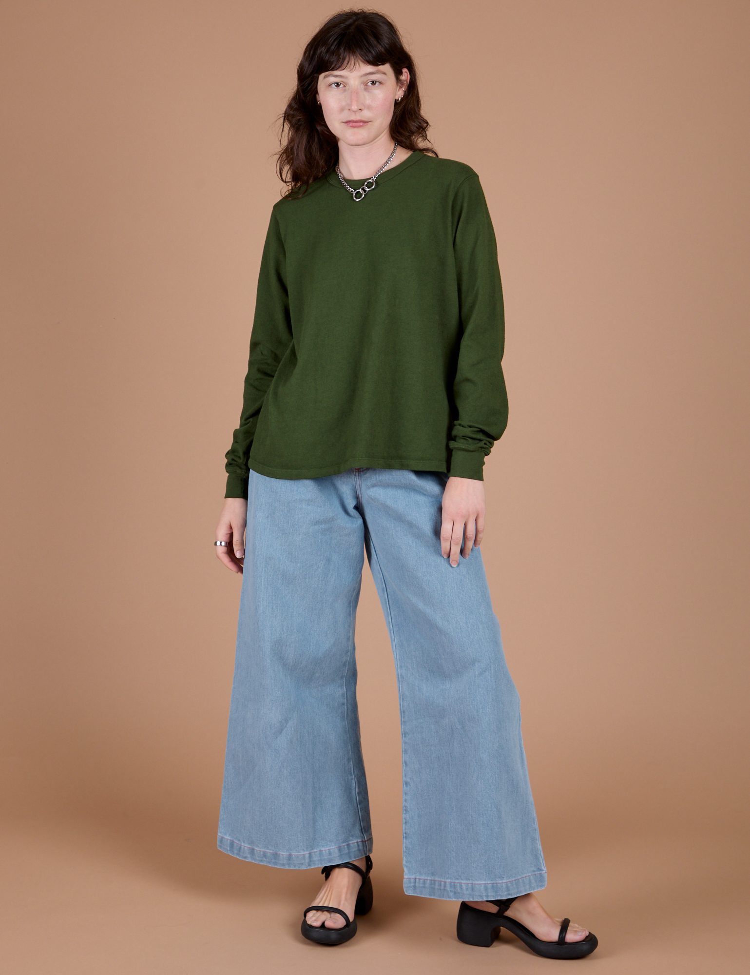 Alex is wearing Long Sleeve Burly Tee in Evergreen and light wash Wide Leg Denim Trousers