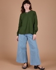 Alex is wearing Long Sleeve Burly Tee in Evergreen and light wash Wide Leg Denim Trousers