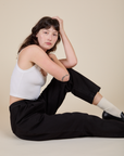 Sitting side view of Heavyweight Trousers in Basic Black and vintage tee white Cropped Tank on Alex