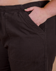 Close up of Juliet's hand in the front pocket of Action Pants in Espresso Brown