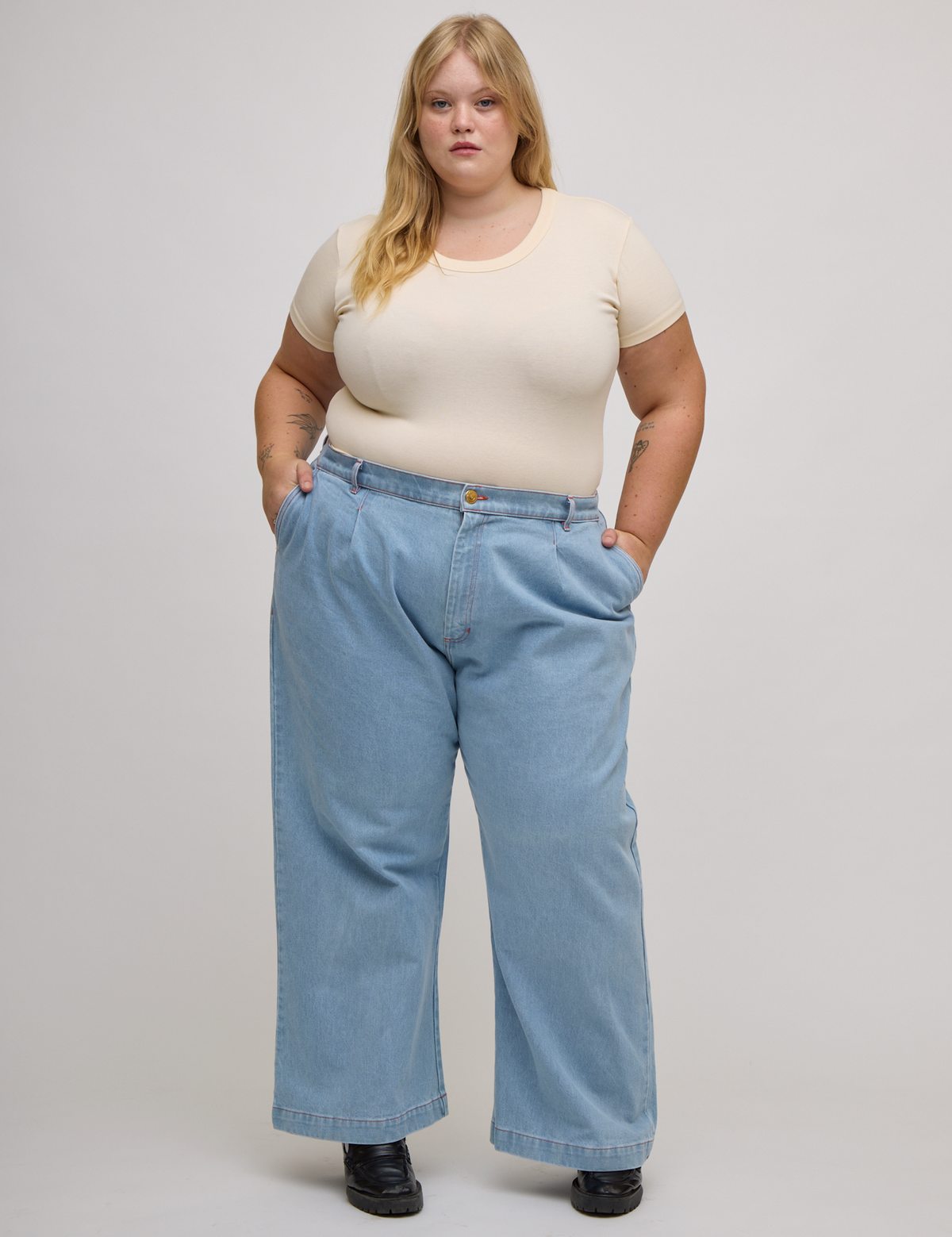 Juliet is wearing  Baby Tee in Vintage Tee Off-White tucked into light wash wide leg denim trousers
