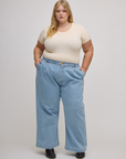 Juliet is wearing  Baby Tee in Vintage Tee Off-White tucked into light wash wide leg denim trousers
