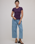 Alex is wearing Baby Tee in Nebula Purple and light wash denim drop pocket pants