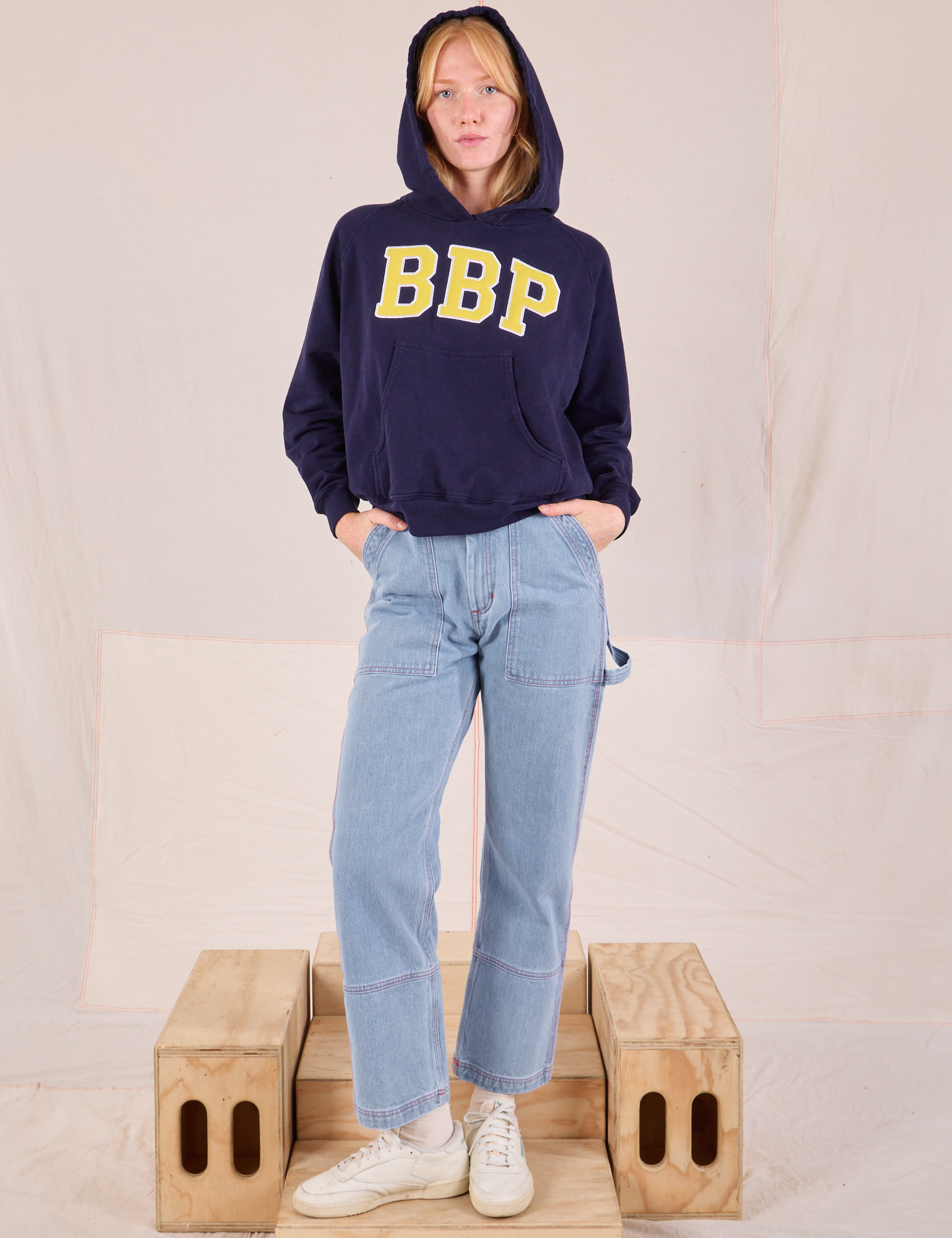 Margaret is wearing Collegiate Hoodie in Navy Blue paired with light wash Carpenter Jeans