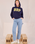 Margaret is wearing Collegiate Hoodie in Navy Blue paired with light wash Carpenter Jeans