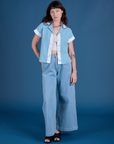 Alex is wearing Painted Pantry Button-Up in Baby Blue and light wash Wide Leg Trousers