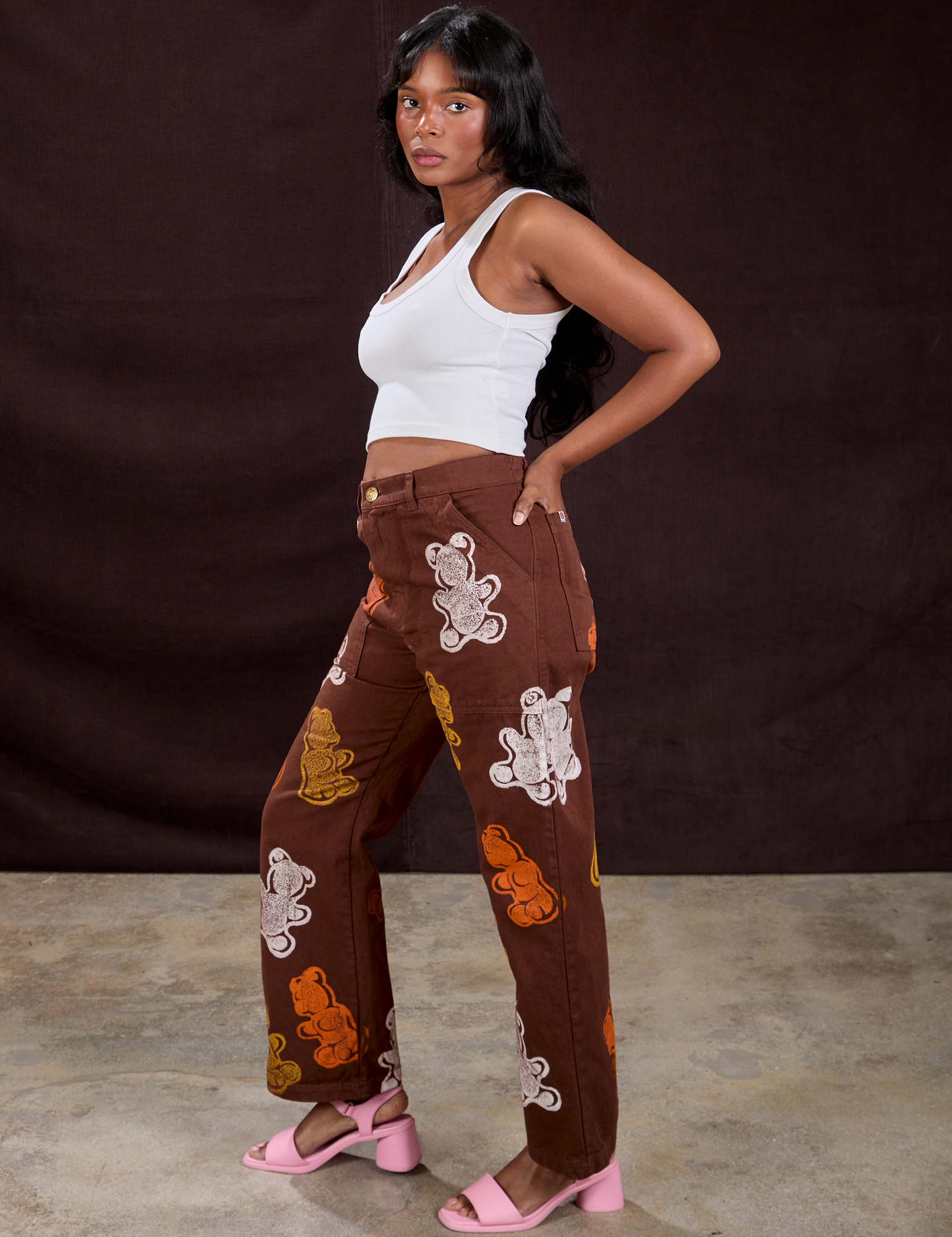 Side view of Gummy Bear Paintstamped Work Pants in Fudgesicle Brown and Cropped Tank in Vintage Tee White on Kandia